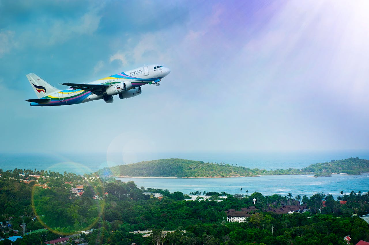hero-img-01 Airplane soaring over Koh Samui island, Thailand, showcasing a vibrant tropical landscape in daylight.